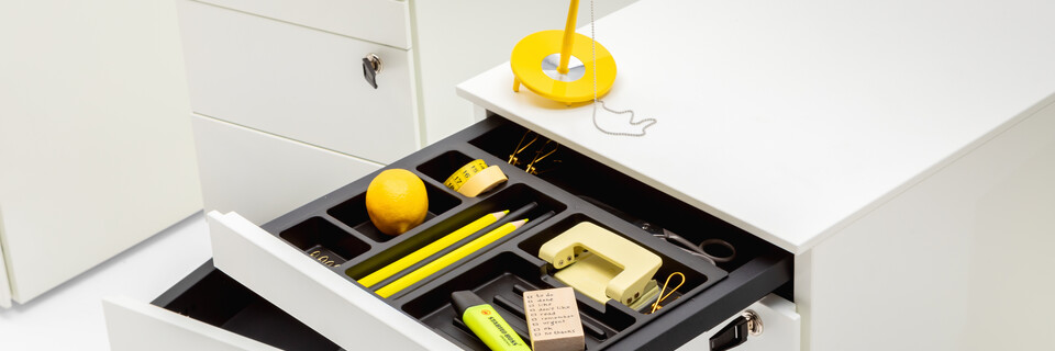 Royal Ahrend Pedestals in white with open pen trays and yellow office supplies front right view