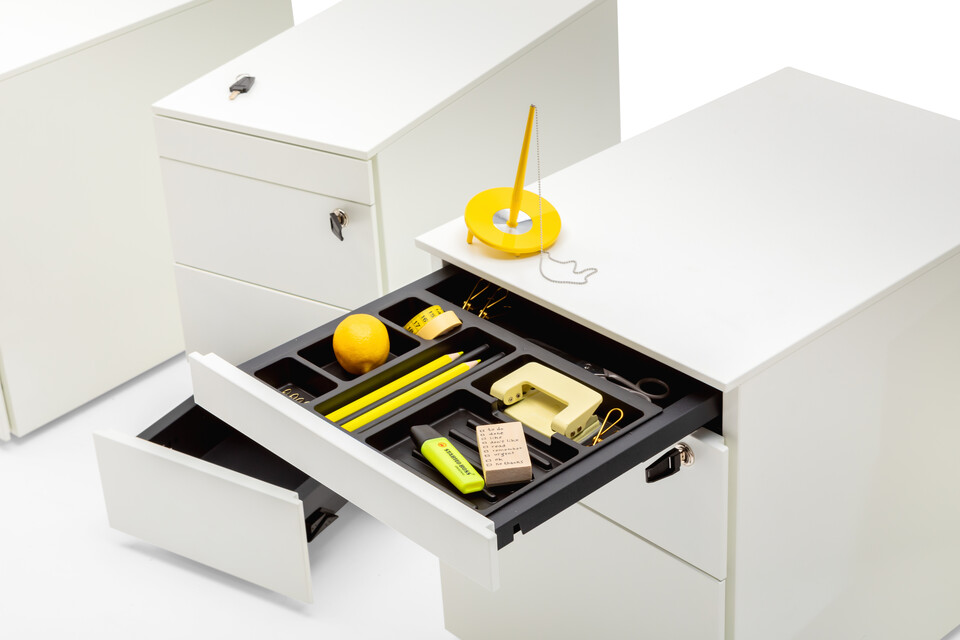 Royal Ahrend Pedestals in white with open pen trays and yellow office supplies front right view