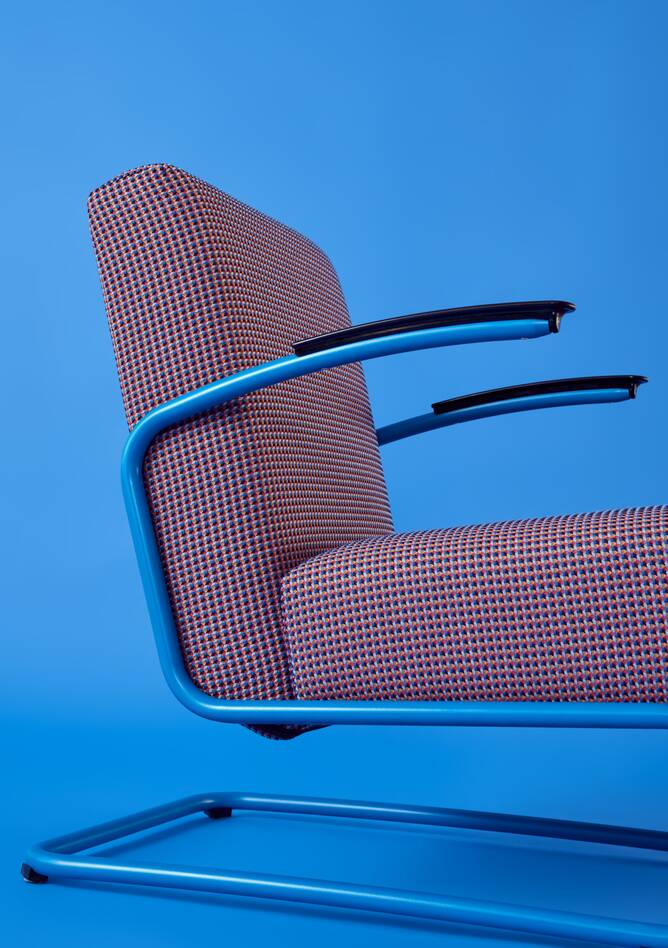 Gispen Classics 405 armchair in blue with multicoloured upholstered seat and back on blue backdrop front left detail view