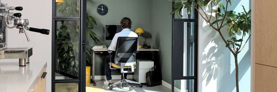 Royal Ahrend balance workstation in grey with oak tabletop and Ease office chair upholstered in yellow and black with male model interior view
