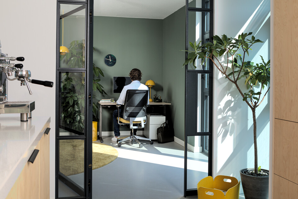Royal Ahrend balance workstation in grey with oak tabletop and Ease office chair upholstered in yellow and black with male model interior view