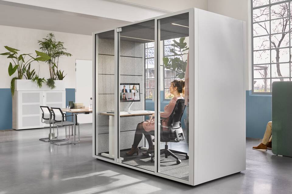 Ahrend Switch and Zinn with Qabin with Ease inside and door closed with SDK with planter in the back with models in a Hybrid working community setting