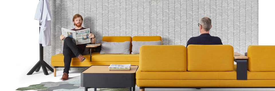 Gispen STEE sofas in black upholstered in yellow with black coffee table and oak top with black Dukdalf coat stand with male models front view