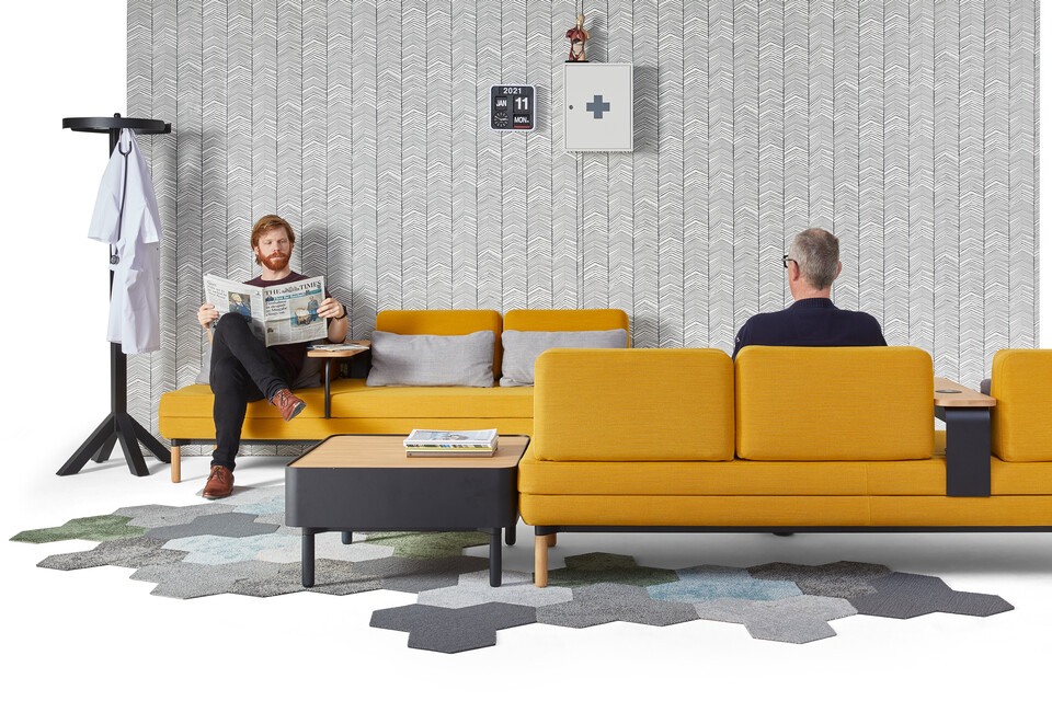 Gispen STEE sofas in black upholstered in yellow with black coffee table and oak top with black Dukdalf coat stand with male models front view