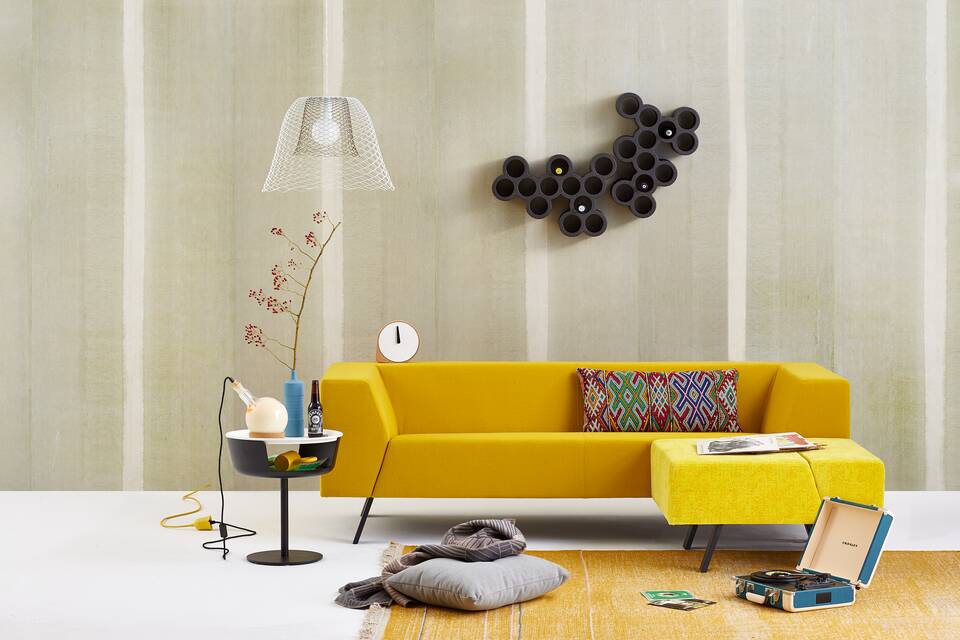 Gispen Sett sofa with yellow upholstery and Asy sidetable with Slingerlamp pendant lamp and carpet and record player in front of light green background front view