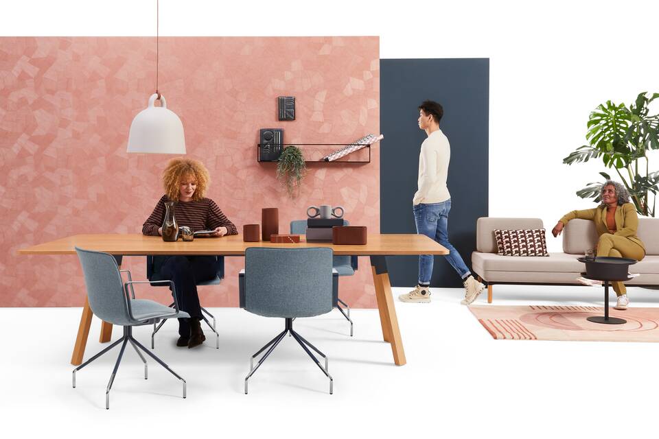 Gispen NOMI Work chair with blue upholstered cover and TEAM Wood rectangle with STEE sofa in hotelification setting with models front view