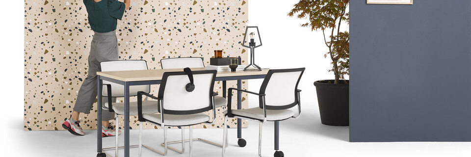 Gispen UT round 4 leg table in blue with oak tabletop on castors and model with grey ZINN conference chairs styled and backpanels front left view