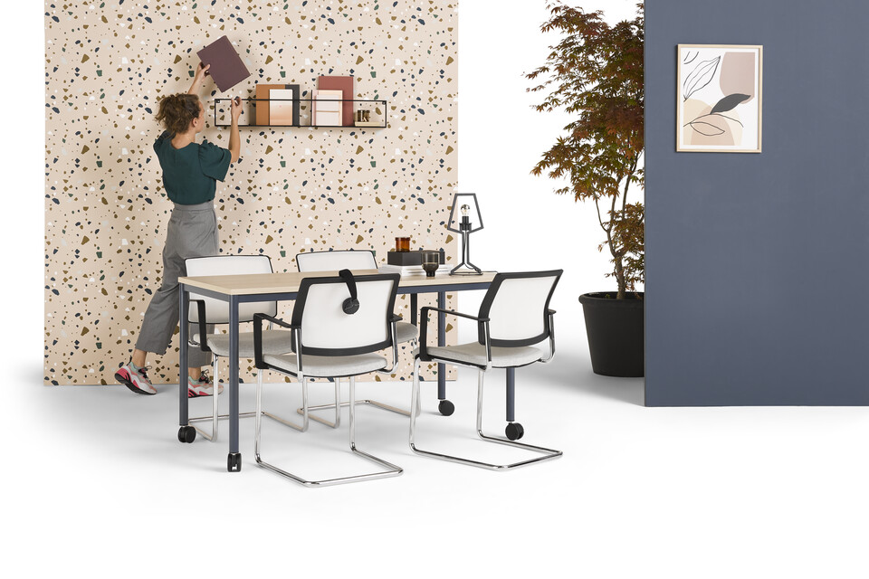 Gispen UT round 4 leg table in blue with oak tabletop on castors and model with grey ZINN conference chairs styled and backpanels front left view