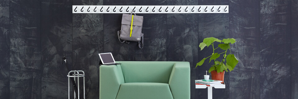 Gispen Sett armchair with green upholstery and 1x6 coat rack and Dukdalf sidetable with brown bag in front of black background front view