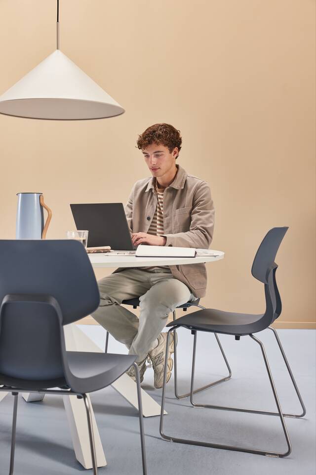 Gispen WIZZ wireframe in blue chairs with white Dukdalf table with male model in a blue beige higher education setting front view