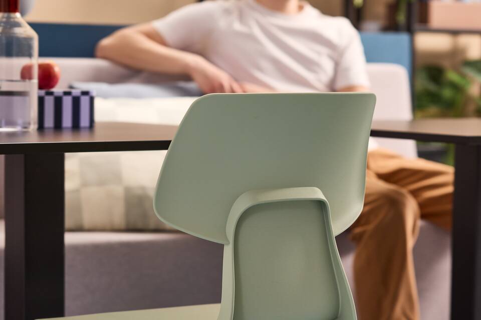 Gispen WIZZ 4 leg chair in green chairs with black framed KOLM table and beige JUNA trainbench in a blue beige higher education setting with model front view