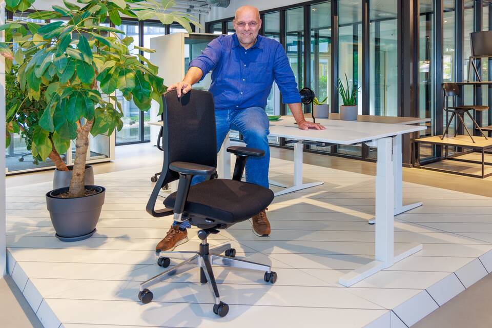 Colour portrait of Robbert de Jonge sitting on desk behind a black office chair