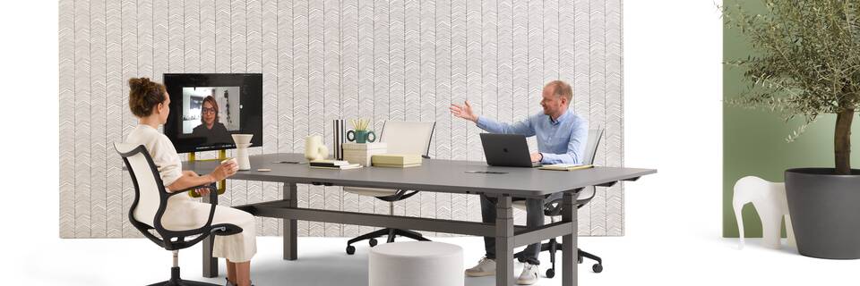 Gispen TMNL Agile table in dark grey with grey tabletop and backpanels with models with Turn chair and grey Asido pouf styled front right view