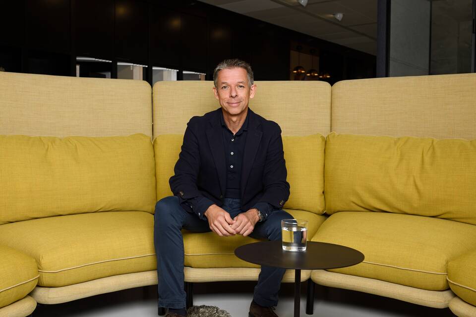 Colour portrait of Eugène Sterken sitting on Embrace sofa landscape