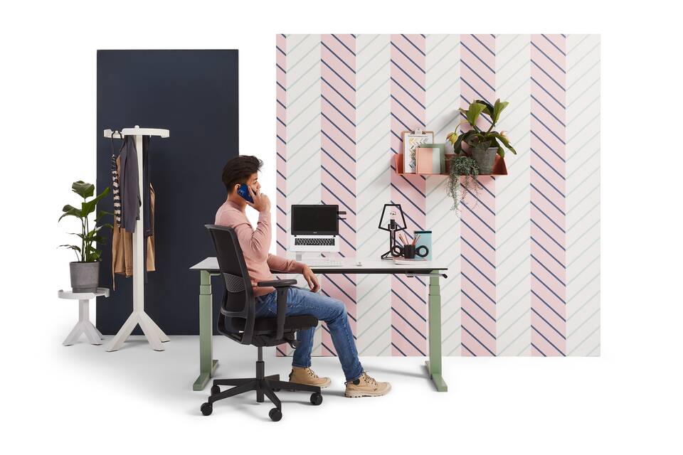 Gispen TMNL workstation with speedcrank in green and Revived tabletop with black ZINN office chair with male model calling with backpanels front view