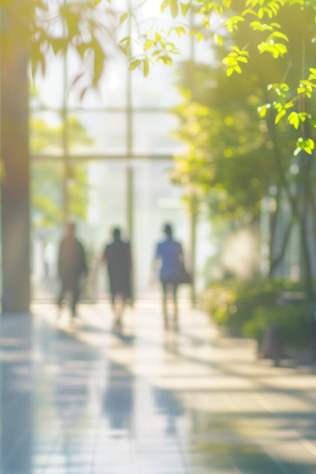 Blurred background of people walking in a modern office building with green trees and sunlight , eco friendly and ecological responsible business concept image with copy space