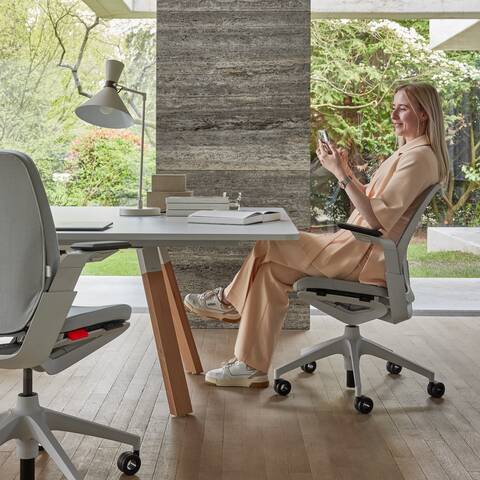 Ahrend Remode office chairs in grey and an Aero bench with model in a colaborative setting right side view