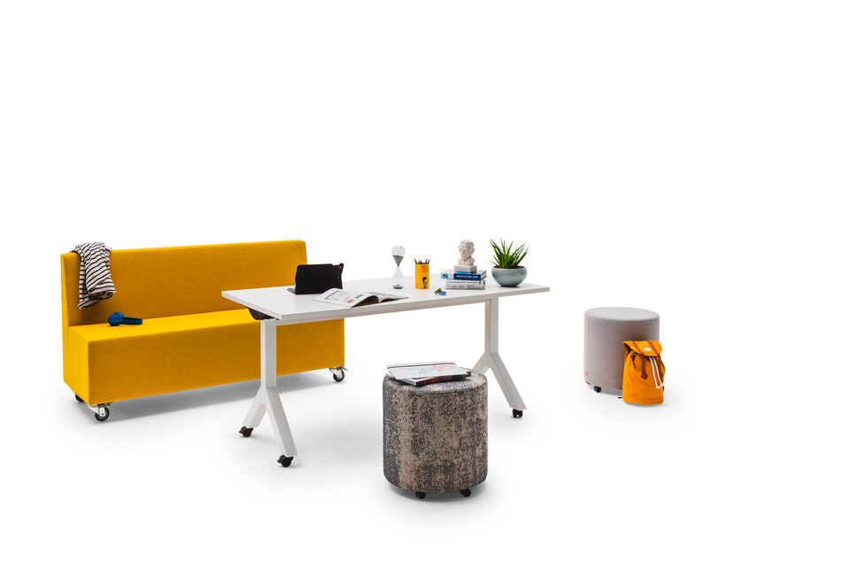 Gispen JUNA Single low trainbench upholstered in yellow with castors and a white Dukdalf folding table with 2 grey Asido poufs front left view