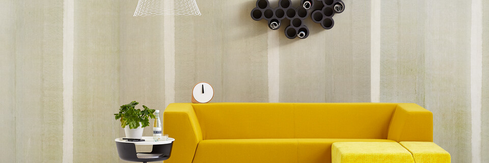 Gispen Sett sofa with yellow upholstery and Asy sidetable with Slingerlamp pendant lamp with plant in front of light green background front view