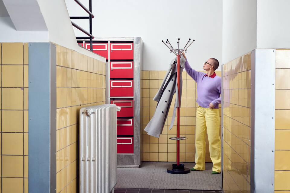 Gispen Classics 1016 coat stand in red with coat and female model in wardrobe at Van Nelle factory front view