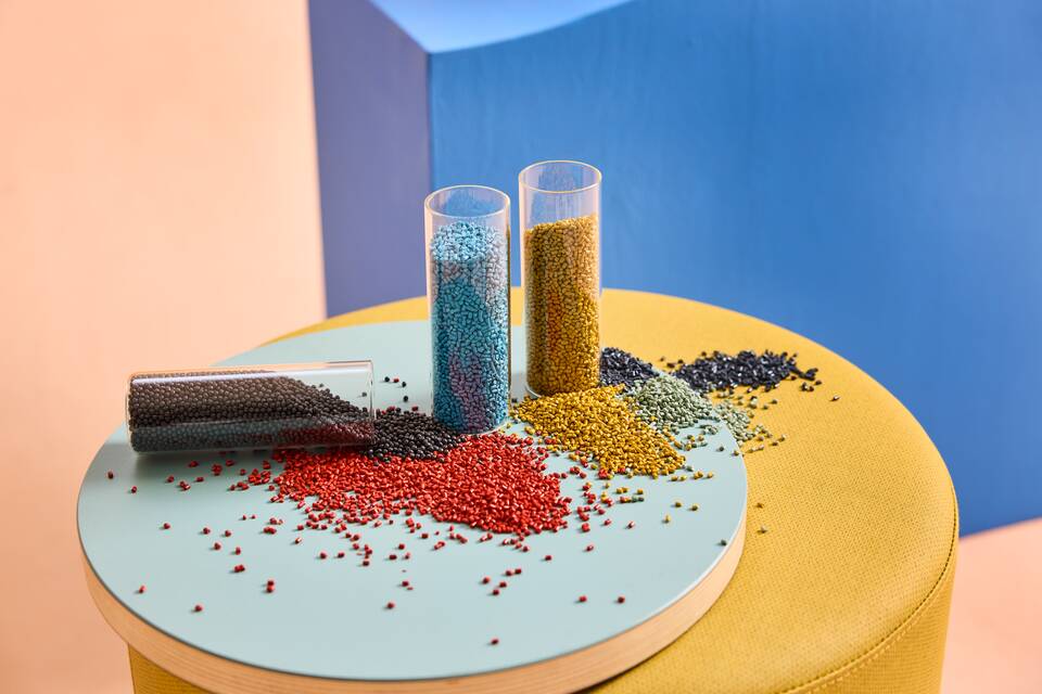 Gispen WIZZ chair material recycled coloured plastic granulate in tubes on a yellow Asido pouf landscape front left view