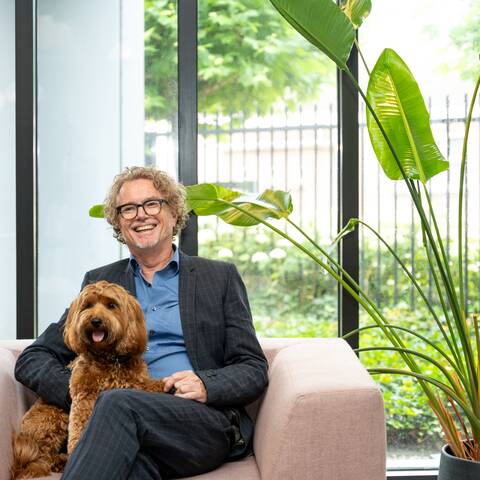 Colour portrait of Rob Lotstra on SETT armchair with dog
