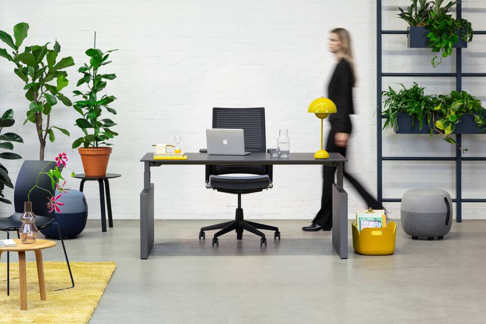 Royal Ahrend Balance workstation in grey with charcoal top and 2020 office chair with female model walking front view