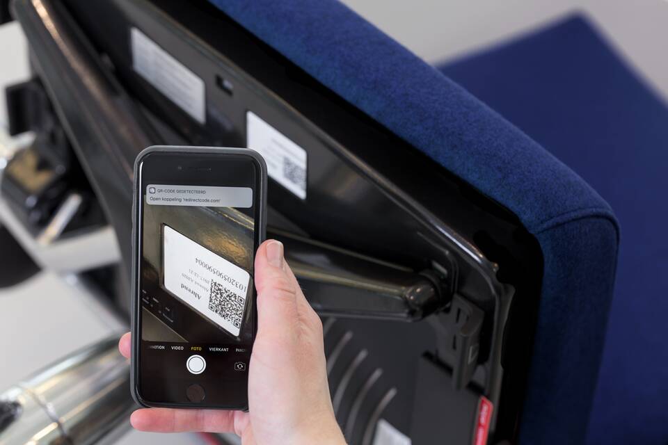 Royal Ahrend service Asset Management female model holding phone scanning blue office chair QR code under seat bottom view