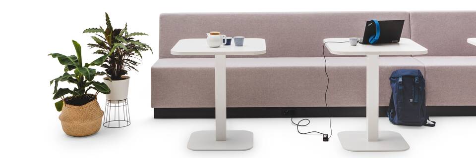 Gispen JUNA Single low trainbench upholstered in grey with 2 white KOLM column tables and styling front view