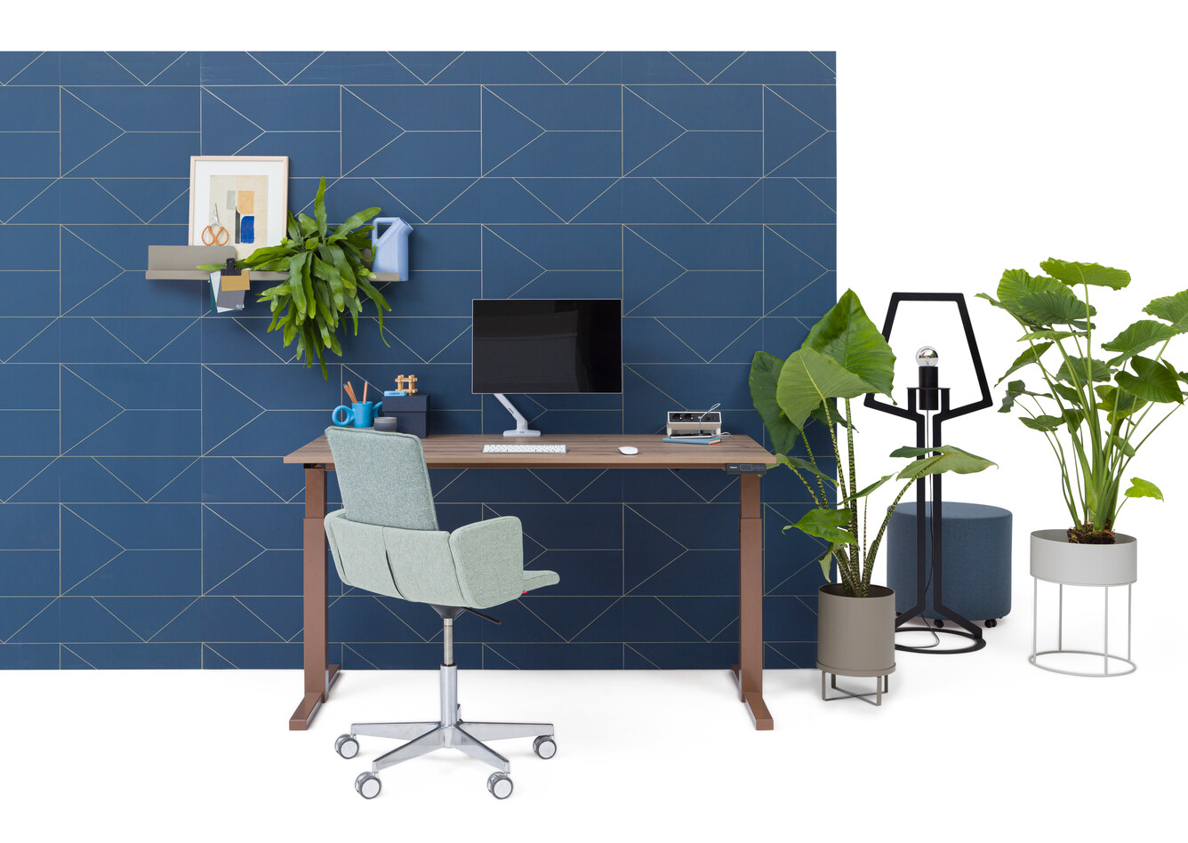 Gispen TMNL workstation in brown with walnut tabletop halfway in stand position and green upholstered green Triennial Manage chair in front of blue backpanel front view