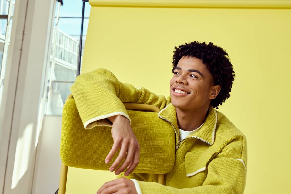 Gispen Classics 101 chair in yellow on yellow backdrop with male model coffee roastery at Van Nelle factory front right detail view