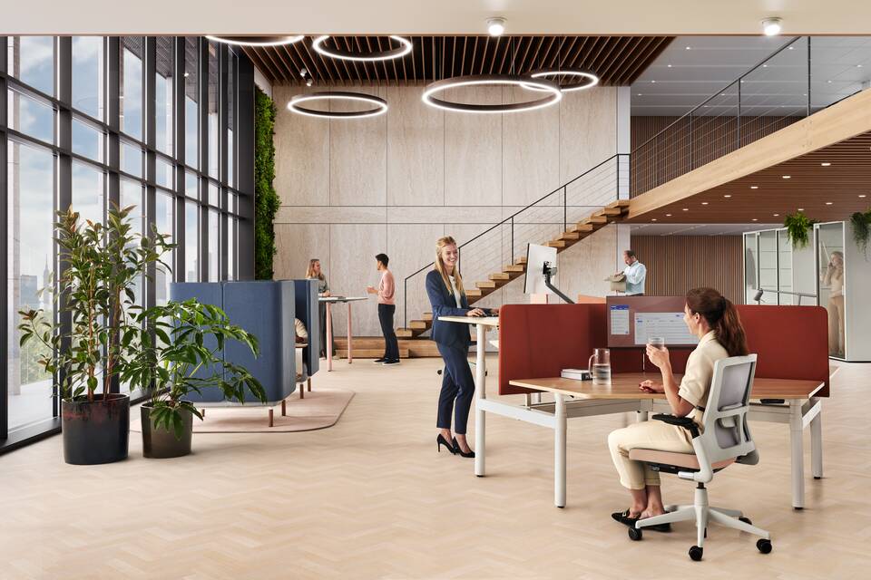 Ahrend Modea sit stand trio workstation in white with oak tabletop and orange S25 screens with models in a vitalising workspace interior view