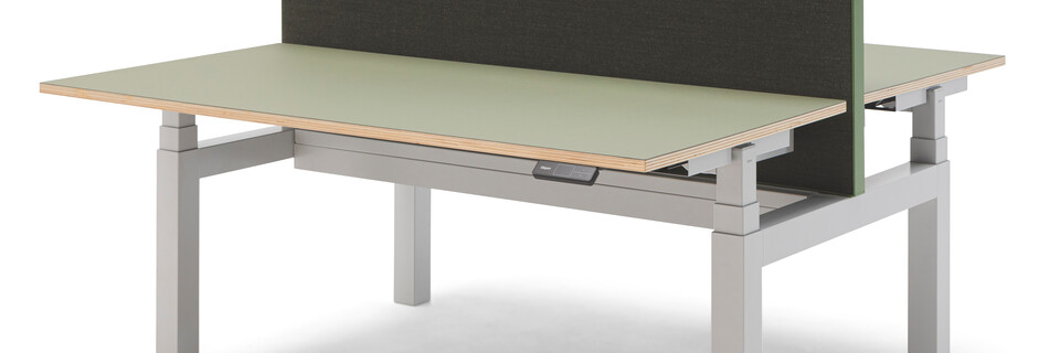 Gispen TMNL dual workstation 3 stage sit stand in light grey with display on the right under green tops and green screen front right view