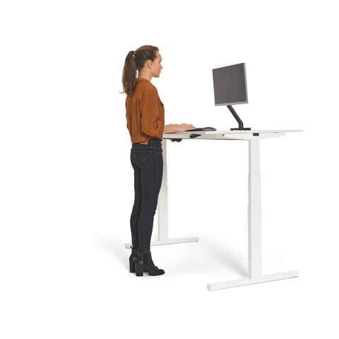 Gispen Home office desk in white and in standing position with female model and eye sight lined with top monitor for ergonomic working front right view