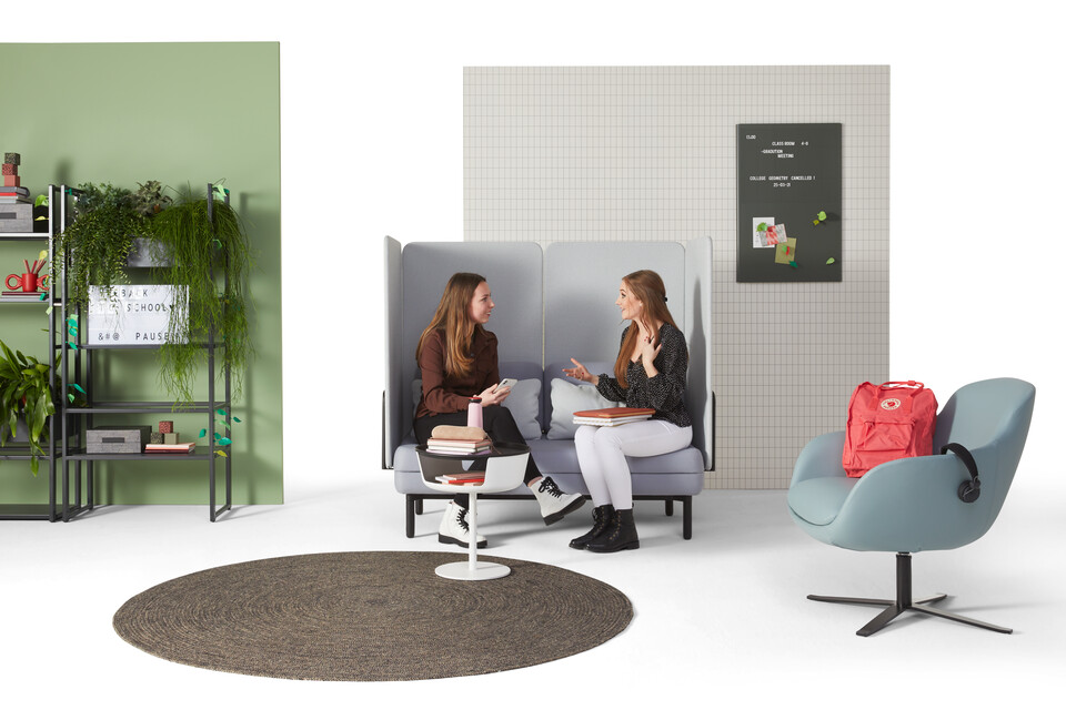 Gispen STEE sofa in black upholstered in grey and light blue with black CIMO Shelving Unit and light blue Queen Low armchair with female models front view
