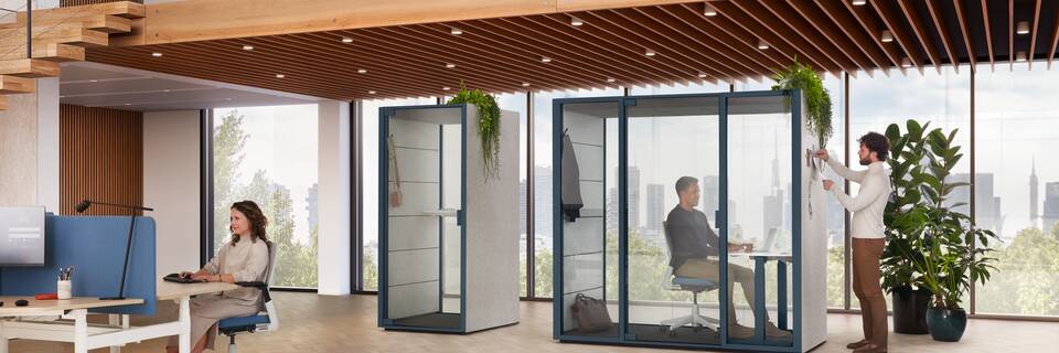 Ahrend Qabin Call and Chat Focus space in space in blue and white Modea trio workstation with blue S25 screen with sitting and standing models in a vitalising workspace interior view