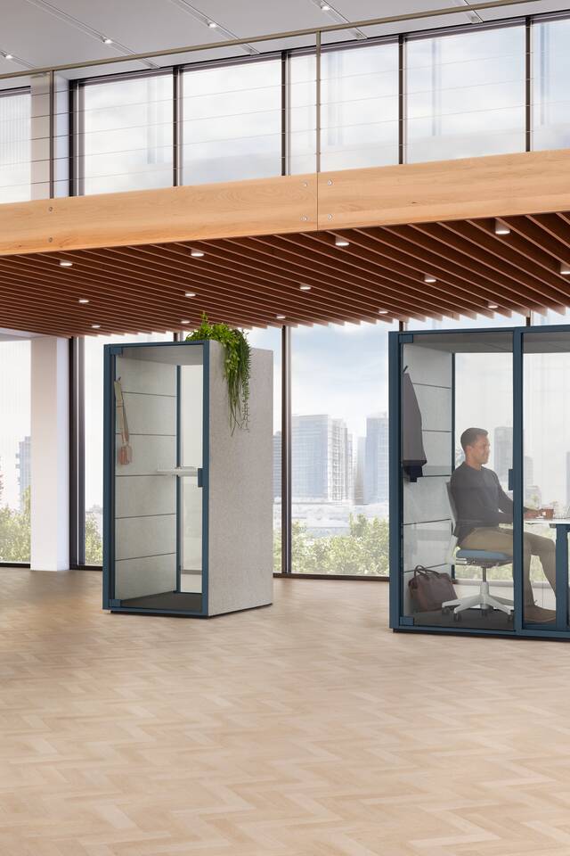 Ahrend Qabin Call and Work space in space in dark blue with models working in a vitalising workspace interior view