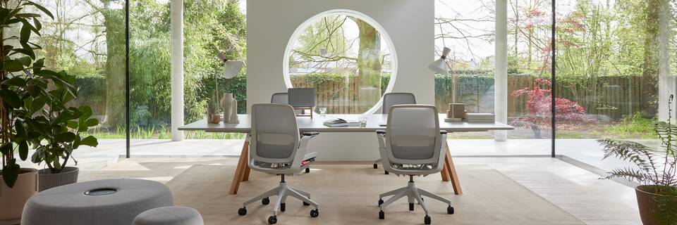 Ahrend Remode office chairs in grey with lumbar support and an Aero bench with Recharge poufs in a colaborative setting rear view