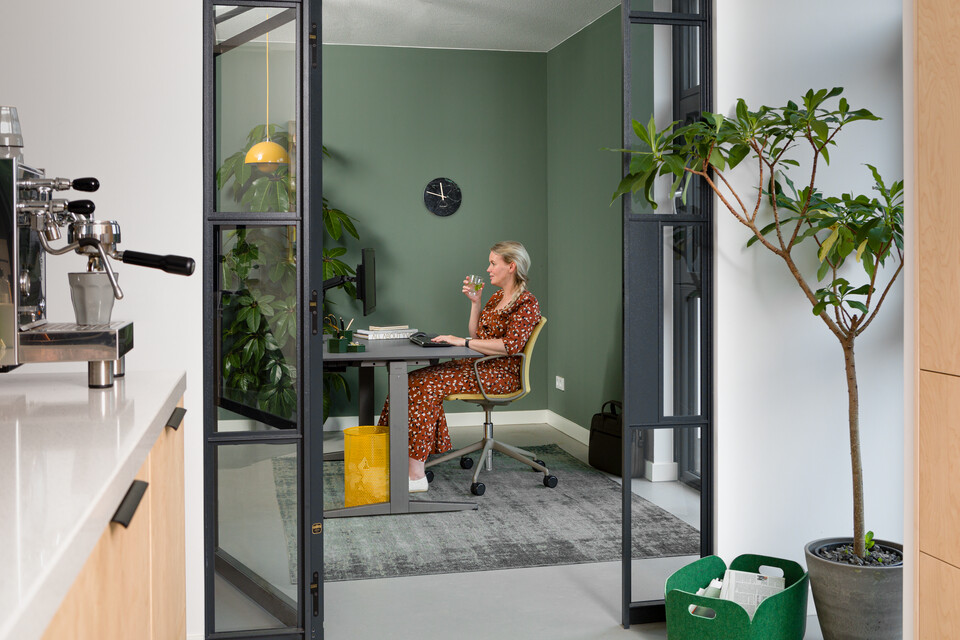 Royal Ahrend balance workstation in grey with charcoal tabletop and Well chair upholstered in yellow and female model interior view