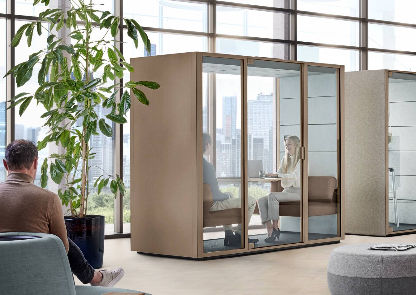 Ahrend Qabin Chat Lounge and Call space in space in clay grey with models and 3 Recharge poufs in a vitalising workspace interior view