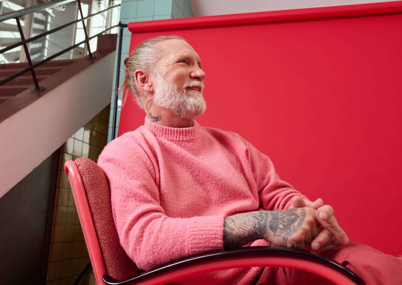 Gispen Classics 412 armchair in red on red backdrop with male model at Van Nelle factory front left detail view