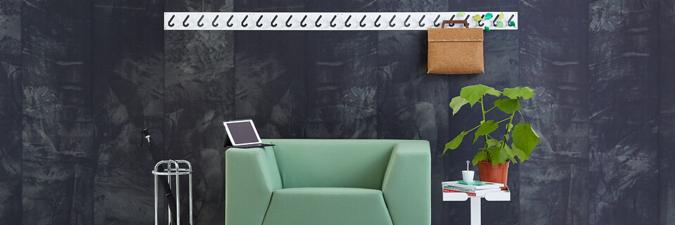 Gispen Sett armchair with green upholstery and 1x6 coat rack and Dukdalf sidetable with grey backpack in front of black background front view