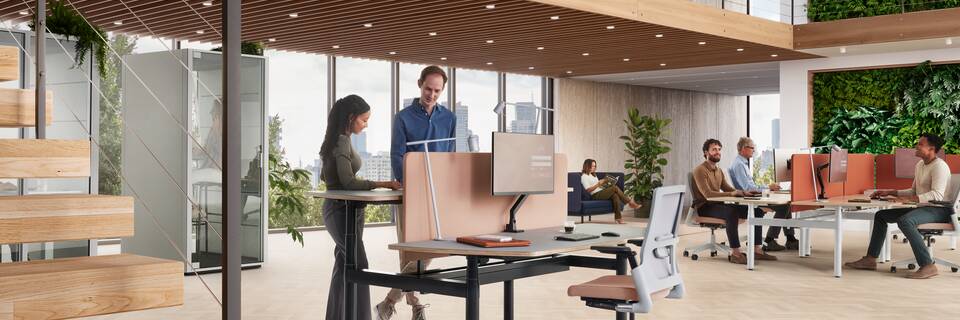 Ahrend Modea sit stand dual workstation in black with grey symmetrical tabletop with standing models in a vitalising workspace interior view