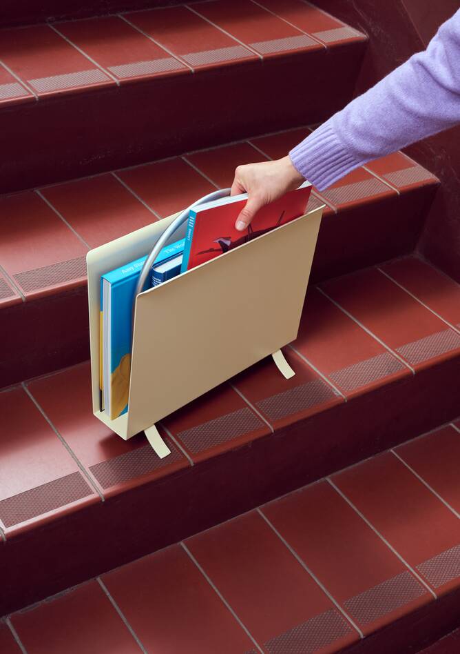 Gispen Classics 1012 magazine rack in yellow with female model arm on stairs at Van Nelle factory front left view