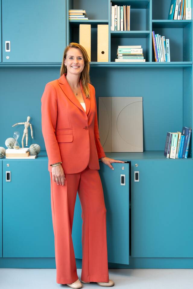 Colour portrait of Annemieke Los in front of blue cabinets variant 1