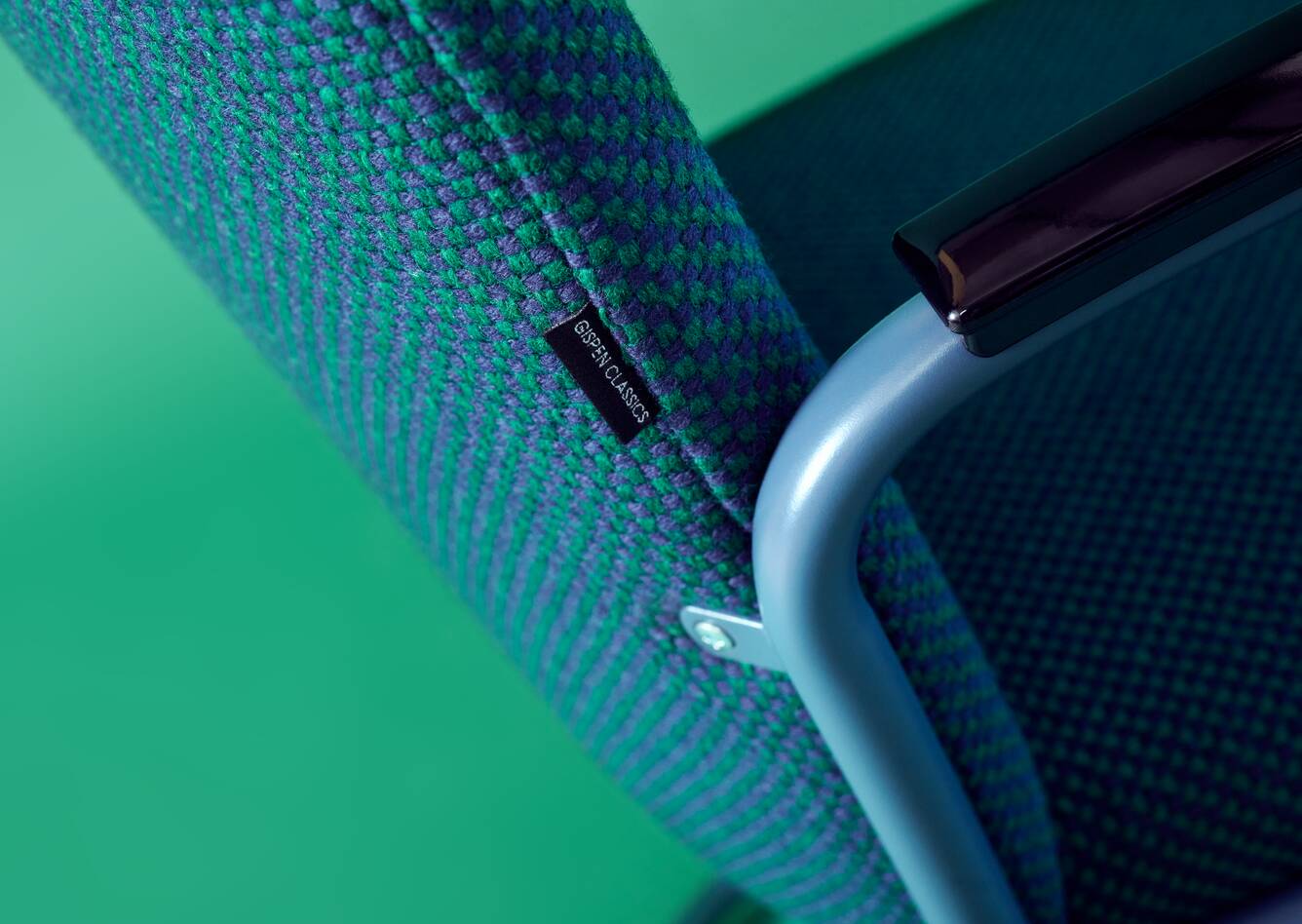 Gispen Classics 413R chair in blue with green upholstered seat and back on green backdrop left rear detail view
