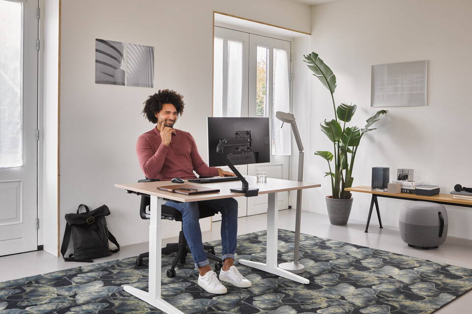 Ahrend Home HVM desk in white with oak tabletop and black A2020 Verta office chair with grey Recharge and Pyramid bench with male model in a work from home setting