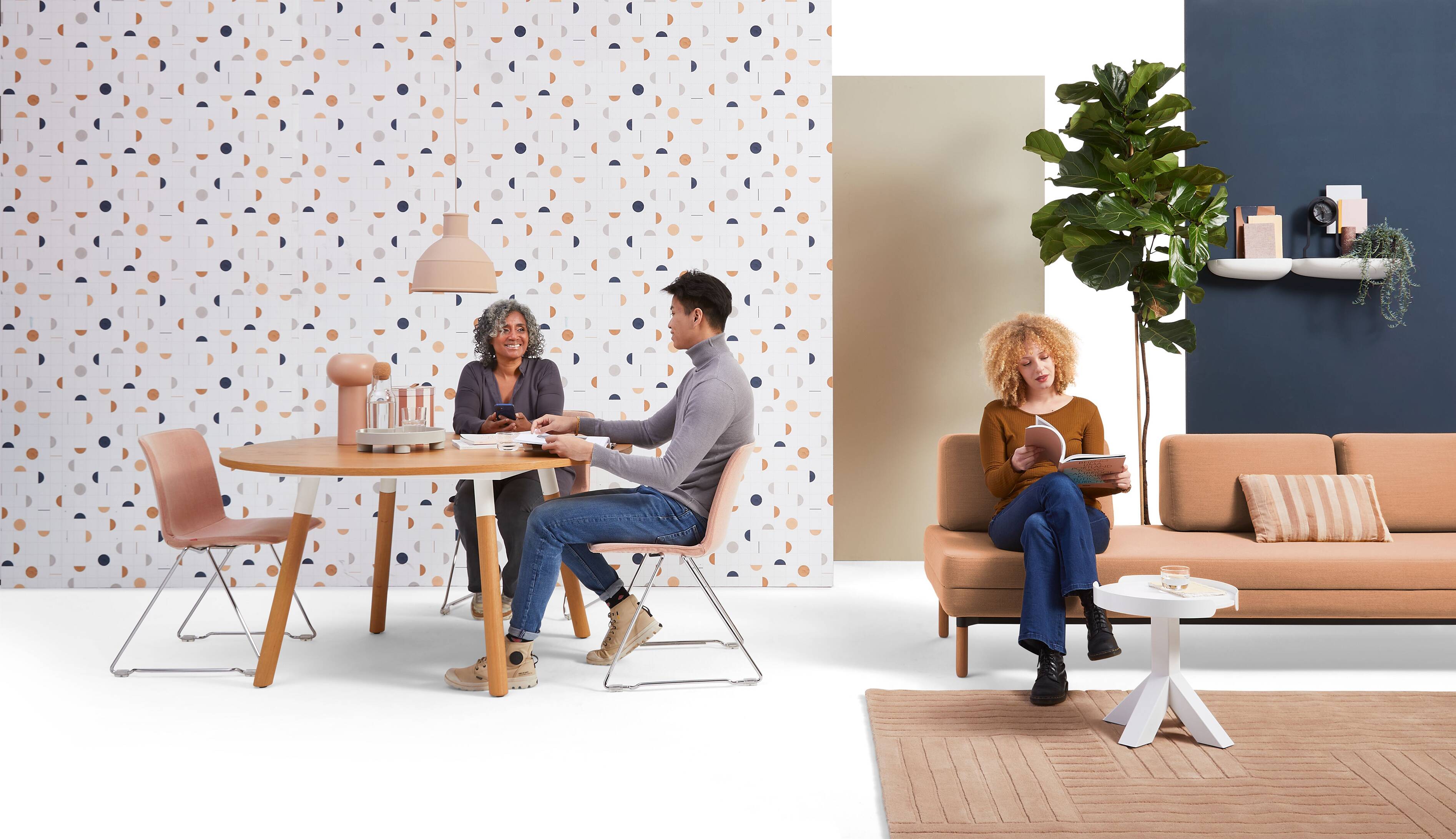 Homepageheader test large Gispen NOMI project chair with red upholstered cover and TEAM Wood round with STEE sofa in hospitality setting with models front view